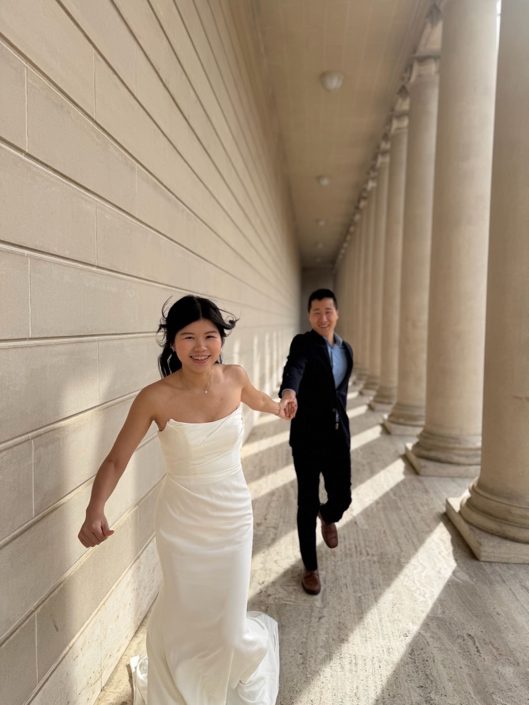 Kimberly leading Walter by the hand along a colonnade